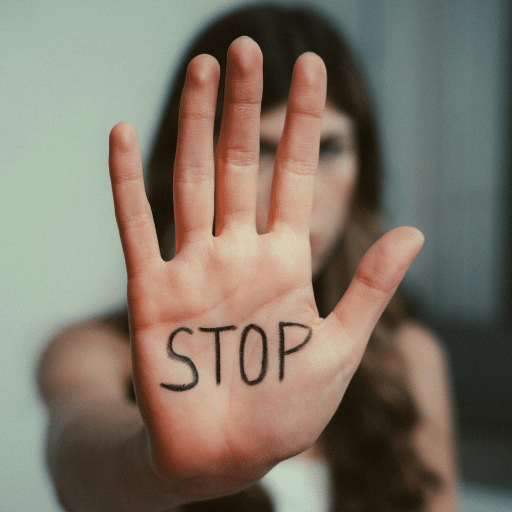 Femme de face tendant le bras pour montrer écrit sur la paume de sa main le mot : STOP