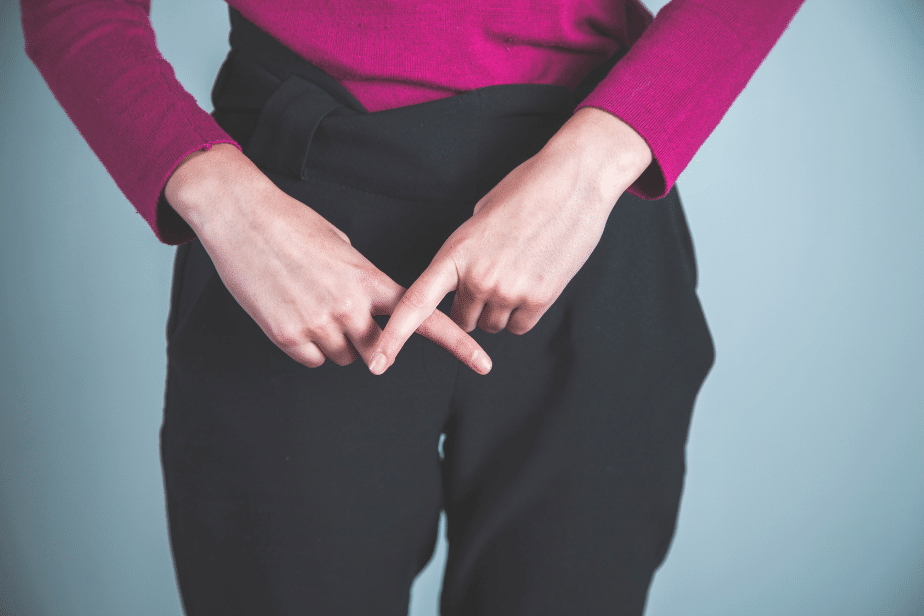 Une femme habillée croise les doigts en forme d’interdiction devant son sexe.